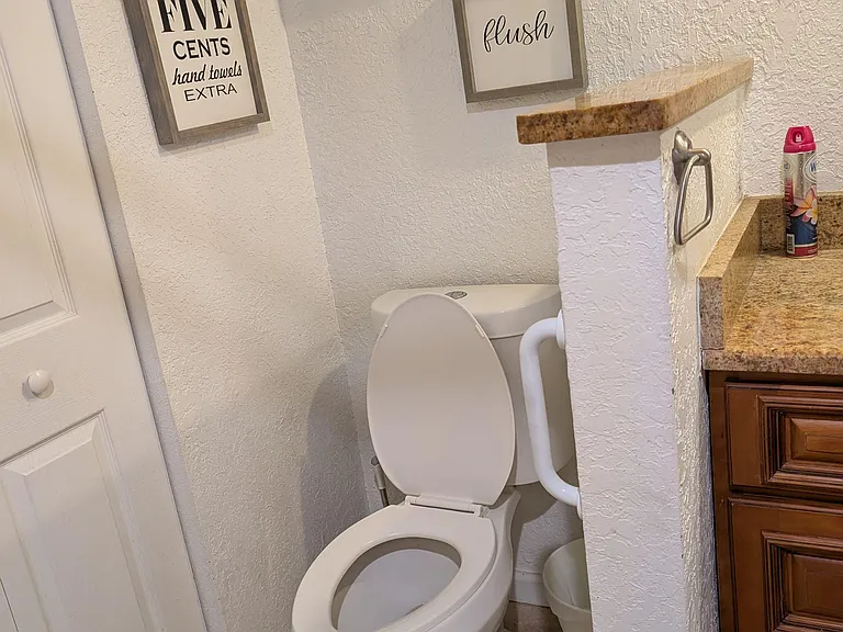 Convenient half bath with toilet, tile flooring, and adjacent vanity counter for everyday essentials.