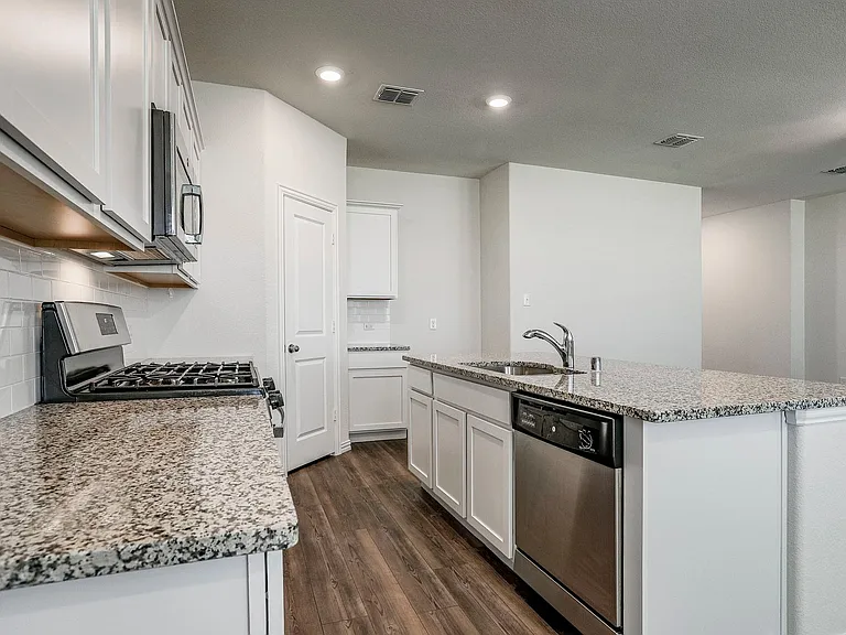 Kitchen with sink, tasteful backsplash, white cabinetry, a center island with sink, and stainless steel appliances