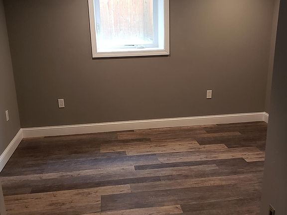 Bedroom with another heat/Ac unit remote control mounted on wall. Bedroom window brings in subtle lighting.