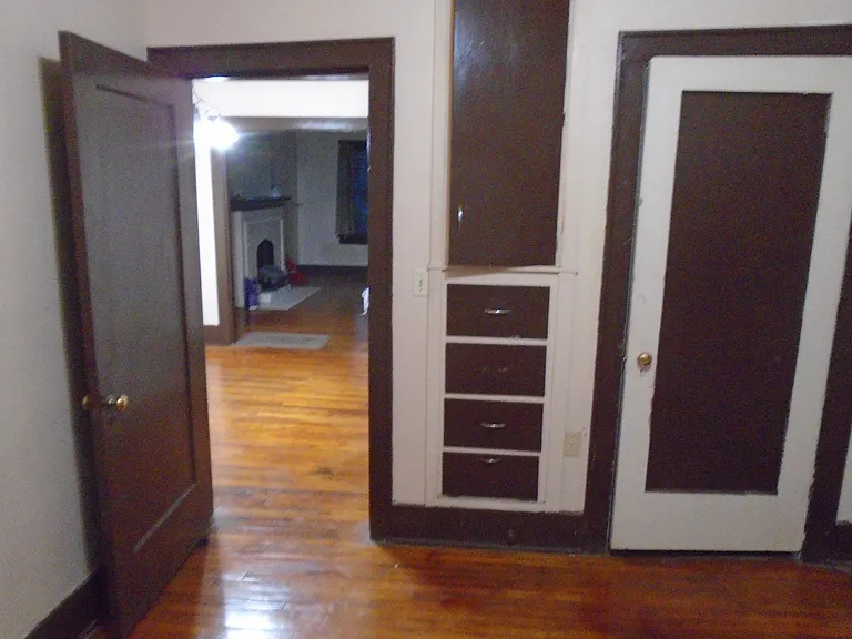 North view of the bedroom wall showing the closed closet door , storage drawers and cabinet door with a view into the dining area, etc.