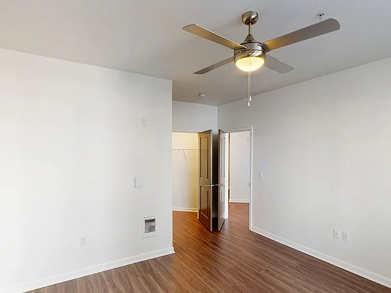 Spacious apartment bedroom with large closet and wood-style flooring.
