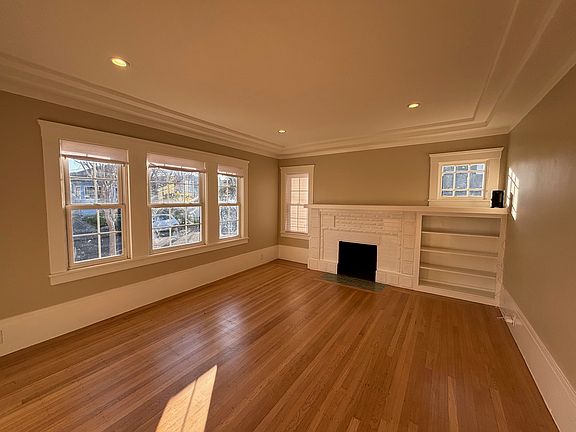 Living room with faux fireplace and built in shelving, lots of light