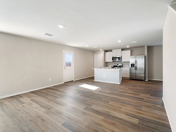 Open Kitchen with an island with sink, appliances with stainless steel finishes, white cabinets, open floor plan, and recessed lighting