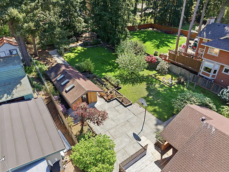 Aerial view of the expansive, fully fenced backyard with gazebo, garden, and towering evergreens