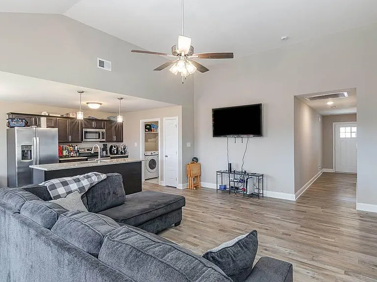 Open-concept living area with plank flooring, ceiling fan, and easy flow into the kitchen with breakfast bar seating.