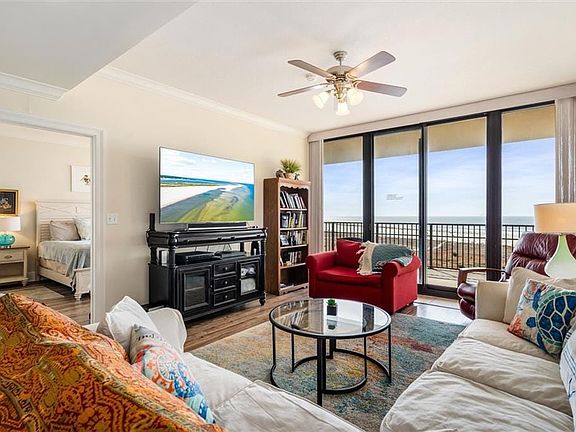 Living room featuring a water view, ceiling fan, hardwood / wood-style flooring, and ornamental molding