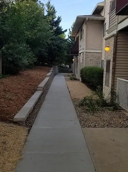 Photo from late 2023 showing new sidewalk and retaining wall. River rock upgraded two years prior. Additional minor landscaping projects ongoing this summer.