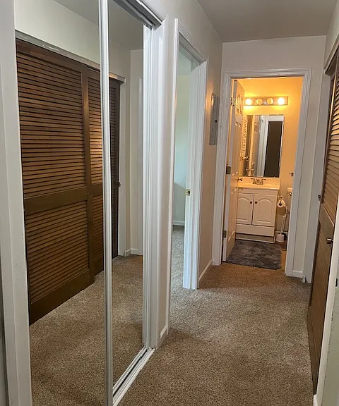 Hall view into the bathroom with master bedroom door open on the left, mirrored closet on the left and utility room with washer/dryer on the right.