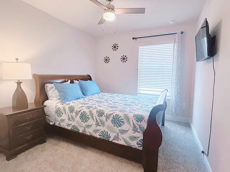 Comfortable mattress queen bedroom with the drawers, smart TV, ceiling fan.