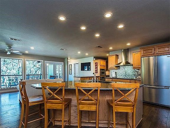 View of the large center island complete with a stainless, Kitchen Aid dishwasher. View into the family room.
