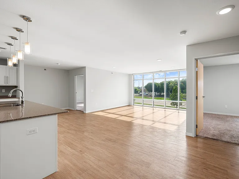 Modern open-concept apartment with sleek kitchen island, large windows, and inviting hardwood floors. Modern open-concept apartment with sleek kitchen island, large windows, and inviting hardwood floors.