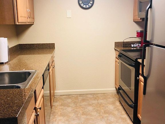 Kitchen with dishes, pits and pans, utensils, blender, coffee maker, Keurig dishwasher, and refrigerator.