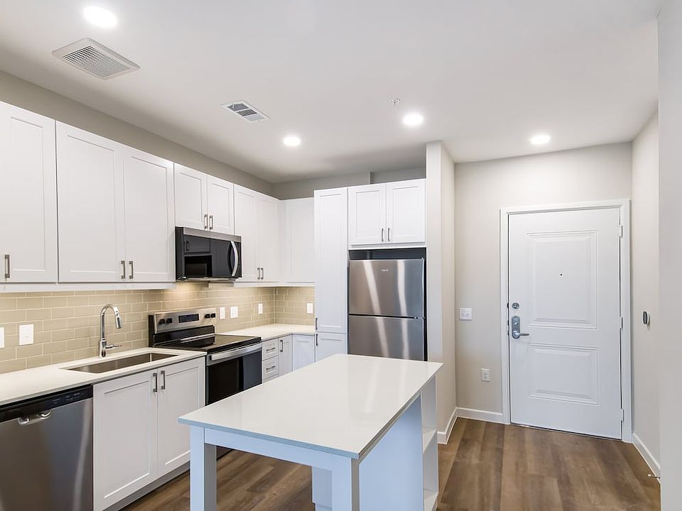 Finish Package I Kitchen with white cabinetry, grey tile backsplash, white quartz countertops, stainless steel appliances, and hard surface flooring