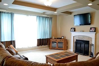Spacious living room (19x17) features creatively textured ceiling beams, massive windows allowing natural light to flow throughout, and a gas fireplace with mantle.