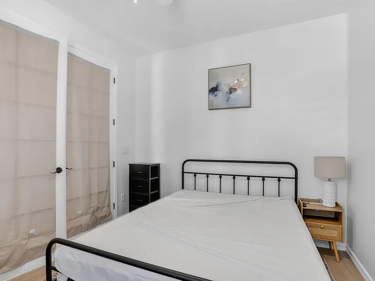 Furnished bedroom with a metal bed frame, nightstand with lamp, and convenient closet storage for everyday essentials.