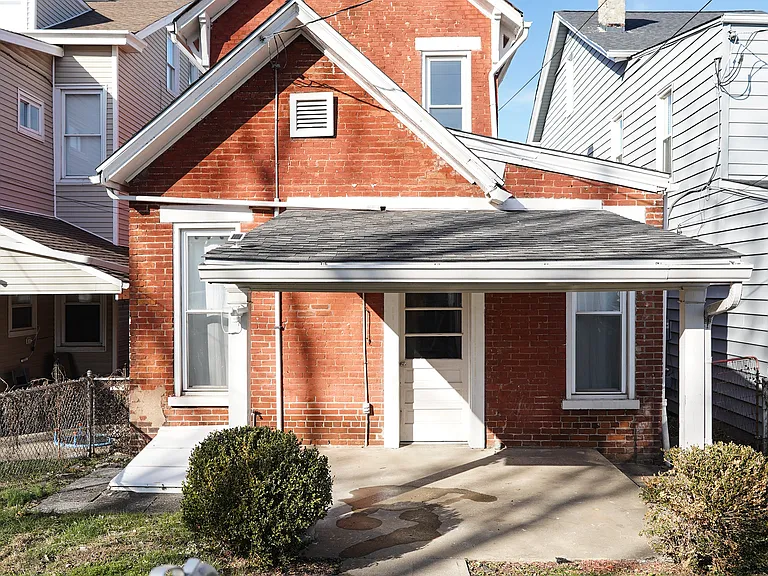 The covered porch is perfect for outdoor living in warm months and helpful cover for bringing in groceries from your dedicated parking pad in back.
