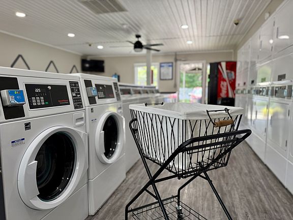 Modern laundry room featuring state-of-the-art washing machines and a stylish laundry cart, ideal for convenient and efficient living.