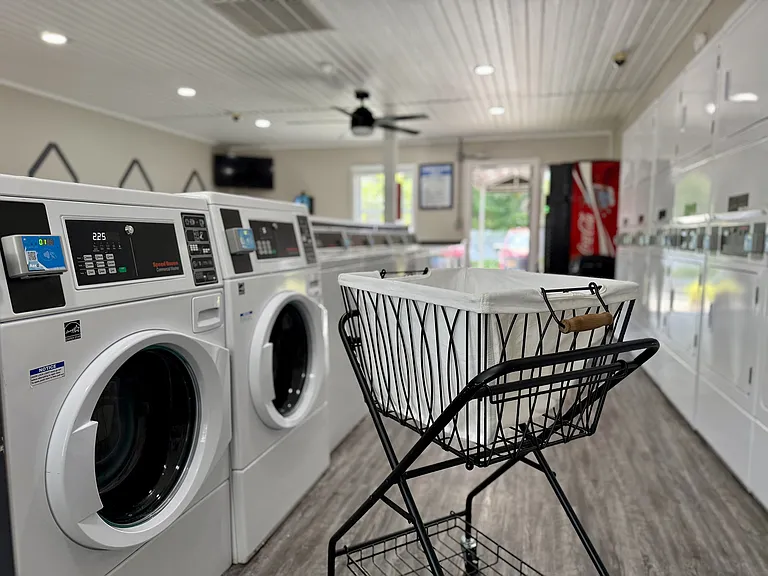 Modern laundry room featuring state-of-the-art washing machines and a stylish laundry cart, ideal for convenient and efficient living.