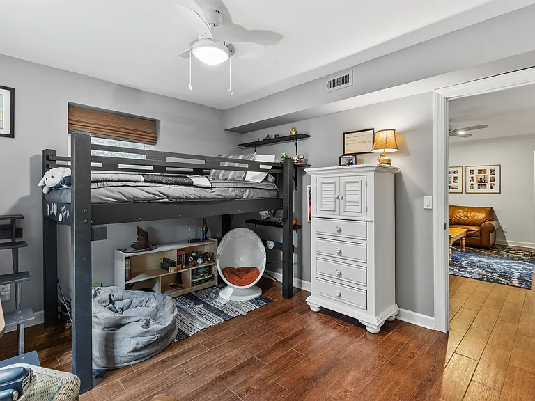 Bedroom #3 with a lofted twin bed, rocking chair, room-darkening shades, dresser, and a ceiling fan.