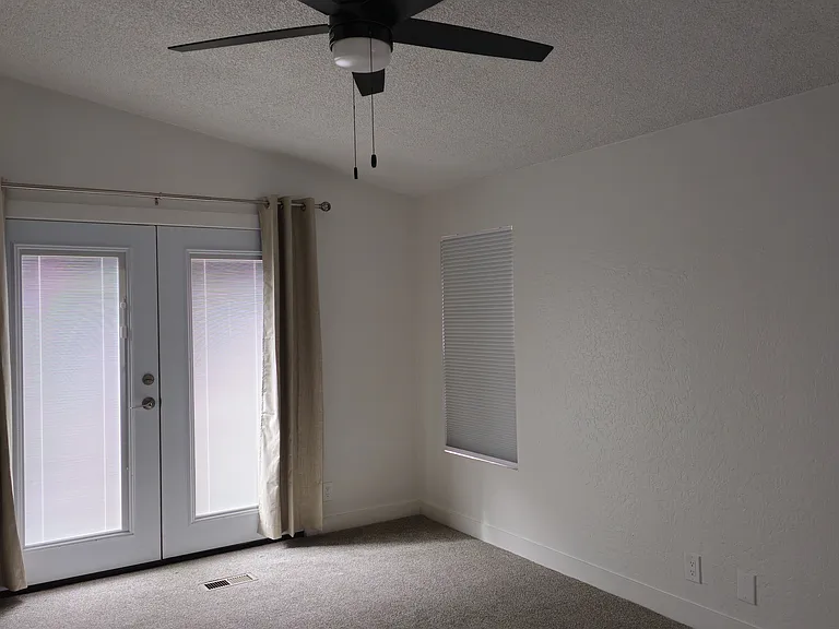Master bedroom with french doors leading into backyard, + ceiling fan