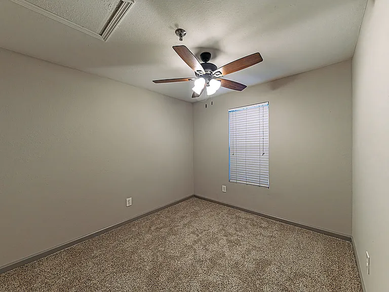 Embrace comfort in this serene bedroom featuring a ceiling fan and soft carpeting.