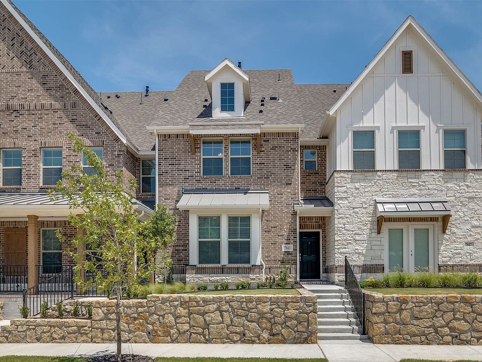 Contemporary townhome facade featuring a blend of brick and stone masonry, board-and-batten siding, multiple gables, and a prominent front entrance with a dark door