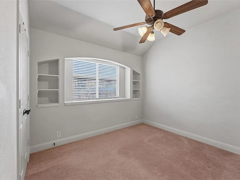 2nd bedroom downstairs with carpet featuring built in shelves, a ceiling fan, and vaulted ceiling