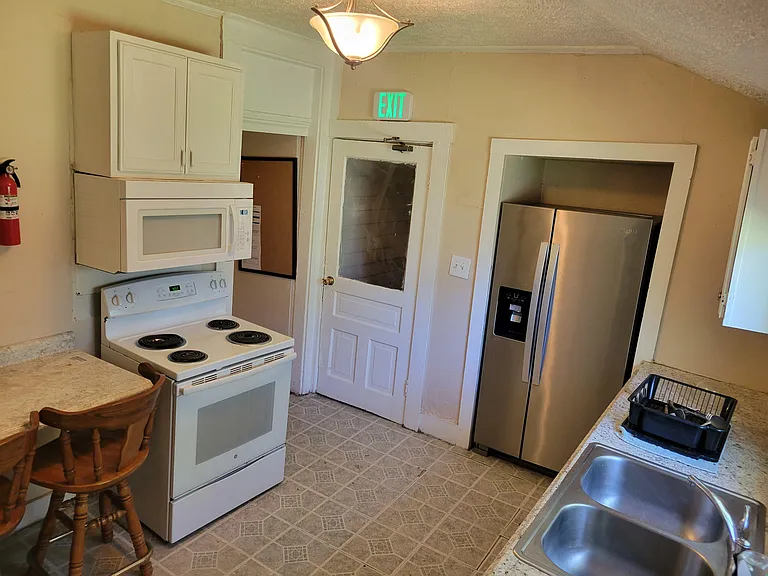 Functional kitchen with full-size range, over-the-range microwave, and stainless side-by-side refrigerator plus ample counter