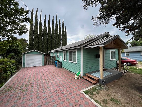 Antique Bronze metal roof and stand alone garage with automatic door, garden gate and side door into garage in breezeway.