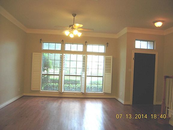 LIving room has high ceilings, crown molding , wooden floors and plantain shutters.