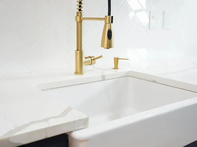 Gold Chef's faucet, soap dispenser, garbage disposal and white ceramic farmer's sink