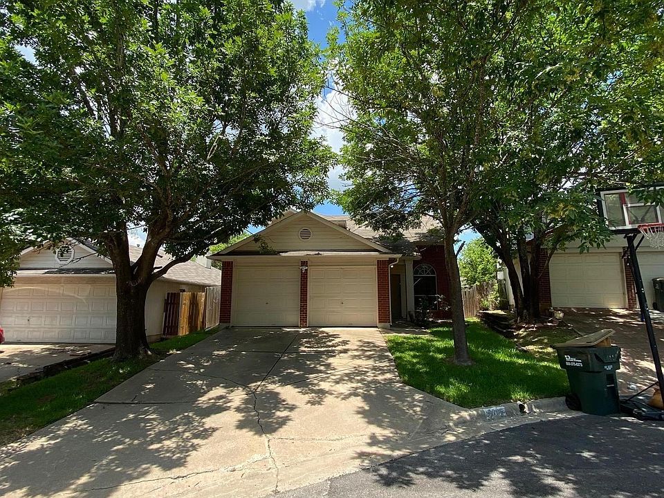 Front of house with a 2-car garage and two gorgeous trees on the east side, offering great shade for the hot Austin summers.