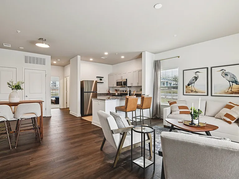 This bright, modern open-concept living space features an elegant kitchen and chic decor to create a seamless and sophisticated environment for everyday living.