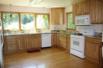 Fantastic updated kitchen featuring pecan cabinetry, wood flooring, granite countertops, updated lighting, windows, and newer appliances!