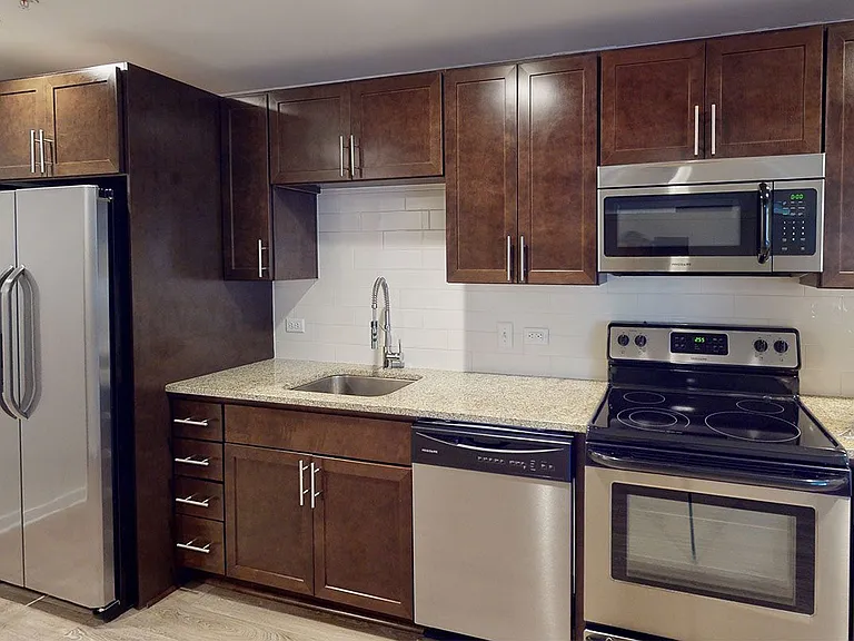 Gourmet kitchen with stainless steel appliances, granite countertops and wood-style flooring.