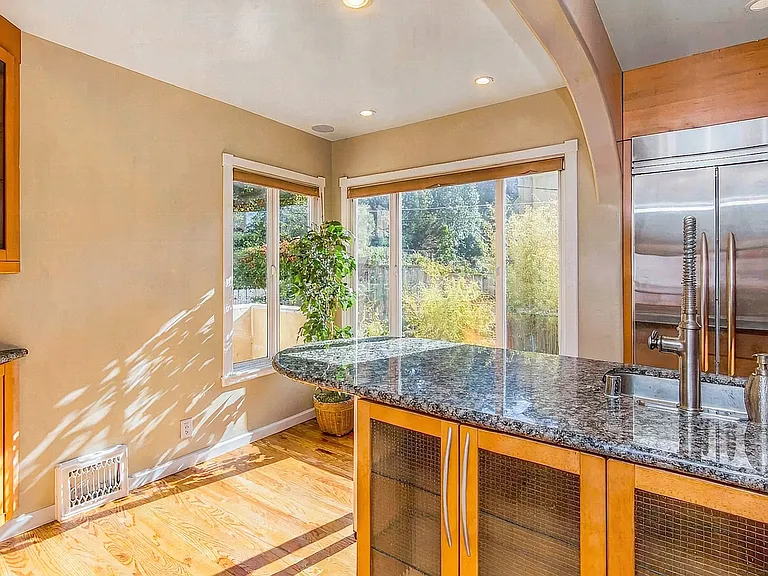 Chef's kitchen with breakfast bar on main level, flooded with natural light. Window to the 1st floor outside deck looking over the garden.