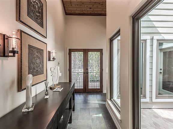 Tranquility and light flood the formal entry way flanked by the stunning kitchen and a private atrium. Beautiful vaulted ceilings with cedar accents add depth to the space.