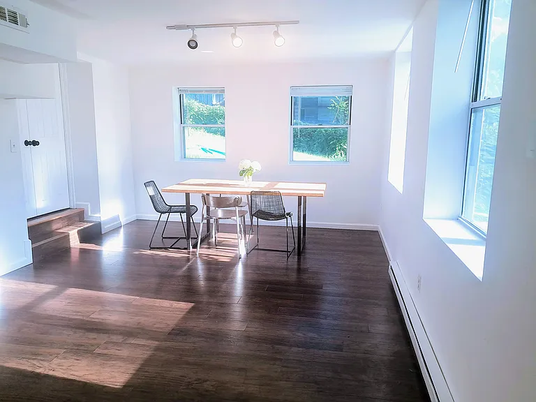 Sunlit living/dining room with full windows on two sides.