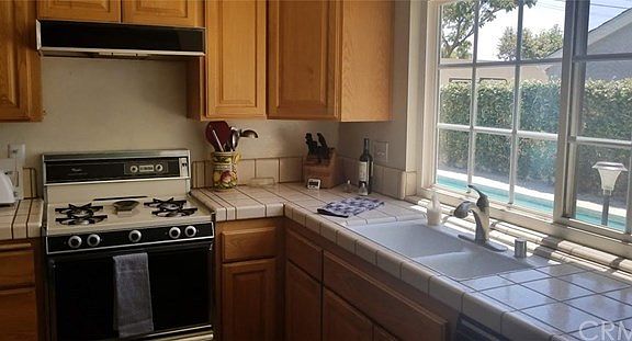 This light and bright kitchen boasts tile counter tops and plenty of cabinetry. It has a lovely wood flooring