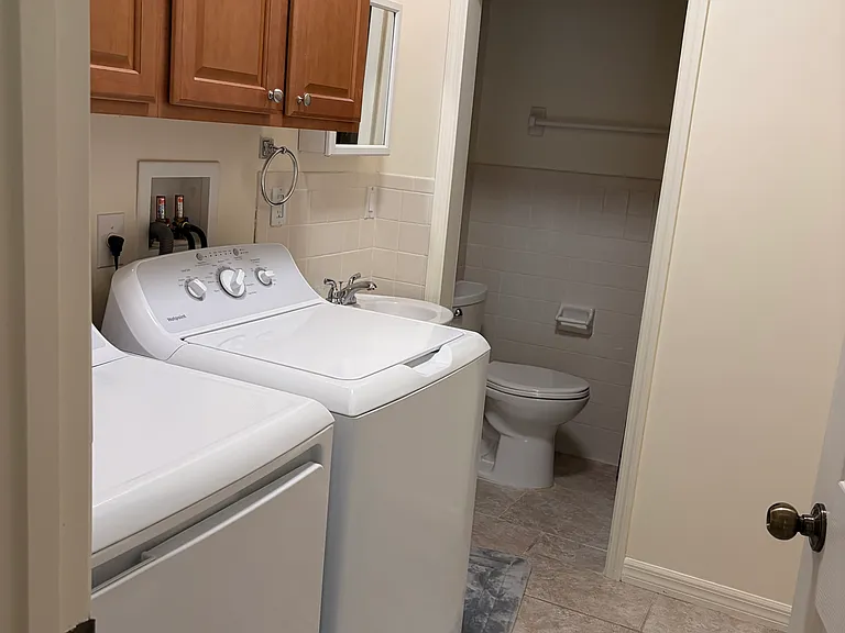 Utility room with washer and dryer. Has plenty of storage space and connected to full bathroom with shower.