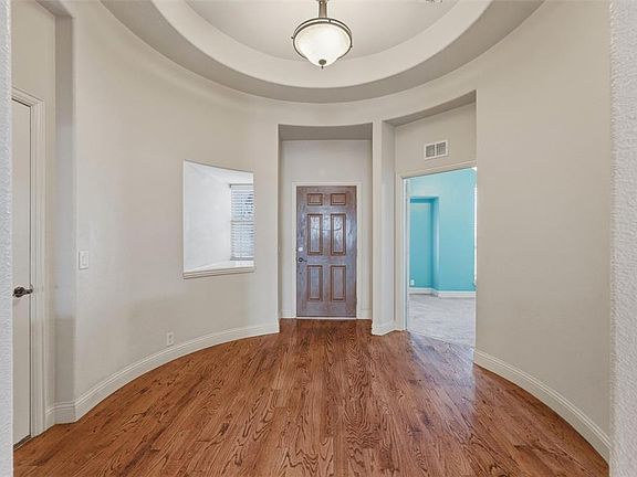 Entrance foyer with wood finished floors and a high tray ceiling