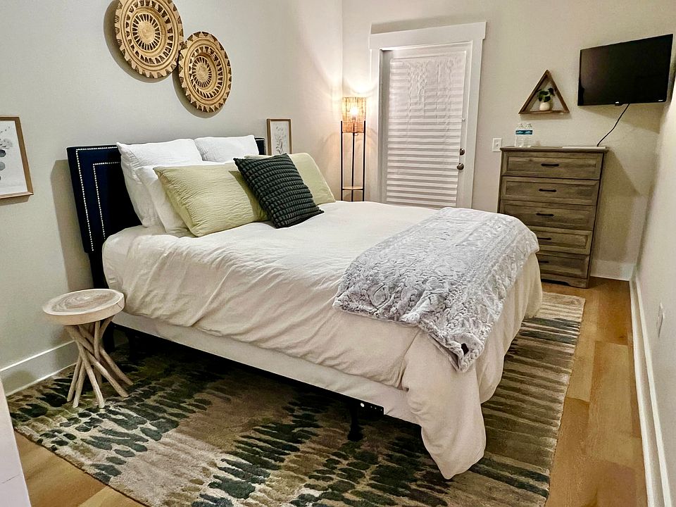 Downstairs bedroom for rent, fully furnished with Queen bed, wall-mounted TV, dresser, side tables, & option for desk.