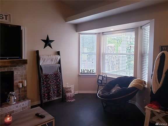 entering the home on the right is the living area with bay window, recessed lighting, gas fireplace, TV nook, vaulted ceiling which opens to the kitchen area and open shelving to store your keepsakes.