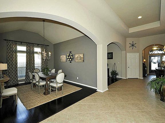 Extremely wide open hallway with tiered ceiling looking at dinning room entrance.