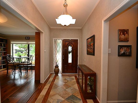Elegant entry offering a front door with beveled glass accents, crown molding, slate tile flooring with wood accents and opens to the living room