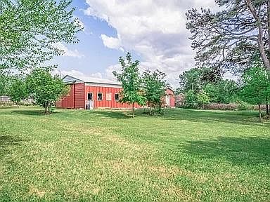East side view of property with large storage shed with electricity. There are pecan trees, pear trees, blackberry bushes, and persimmon trees. Use of 1200 sq ft barn with RV hookup for extra monthly fee.
