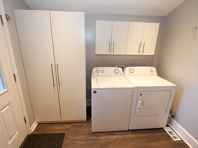 Large laundry room with built cabinets and door to rear yard.