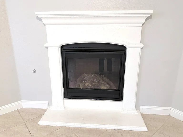 Gas fireplace featuring a classic white mantel, hearth, and black-framed gas insert