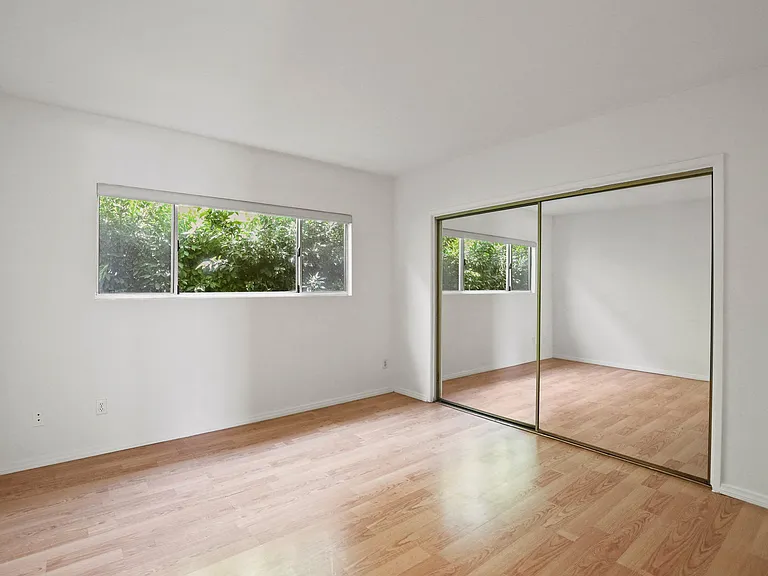 Bedroom with Large Mirrored Closet, Vinyl Flooring, and Windows