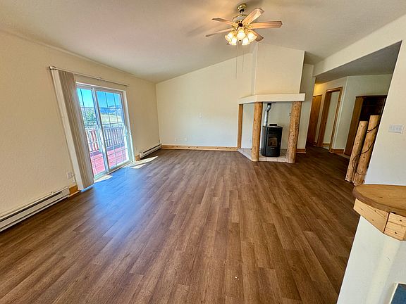 Living area with walk out to deck, pellet stove, ceiling fan and open living area to kitchen.